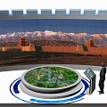 Circular Display Cabinet With Green Model Standing Person And Curved Screen Displaying Snowy Mountain Ancient Architecture