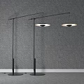 Two Modern Floor Lamps With Sleek Black Poles And Round Shades Against Grey Wall Background
