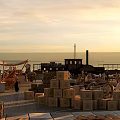 Rustic Swing Door in Seaport Scene with Wooden Crates Sacks Carts and Sunset Sky
