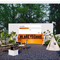 Feature Wall With Orange Circle Text Surrounded By Plants Tables Chairs And Teepee In Garden