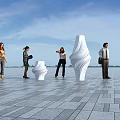 People Standing In Open Square With Gray Tiled Floor And White Sculptures Under Blue Sky