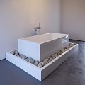 White Freestanding Bathtub On Platform Surrounded By Pebbles With Modern Faucet