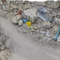 Pile of Construction Debris With Rubble Bricks Metal Sheets Yellow Blue Buckets And Dirt Path