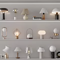 Various Modern Table Lamps With Unique Shapes And Metal Ceramic Bases Displayed On White Shelves