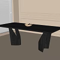 Modern Black Dining Table with Unique Curved Legs and White Bowl in Bright Light-Colored Room
