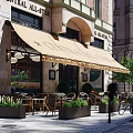 Charming Café Exterior With Outdoor Seating Awning Wooden Tables And Potted Plants