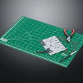 Green Cutting Mat With Craft Tools Scissors Ruler Pliers And Papers On Surface 3d model