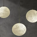 Three Ivory White Spherical Pendant Lights With Moon Surface Texture On Dark Wall