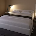 Modern Double Bed With White Striped Bedding Nightstand Lamp Beige Wall And Dark Rug