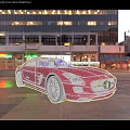 Red Mercedes Sports Car Parked On City Street With Tall Buildings And Lights