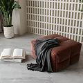 Brown Upholstered Stool With Gray Blanket Open Book Plant And Lattice Screen On Gray Floor