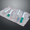 Assorted Medical Syringes Of Different Sizes With Green Plungers On Cloth