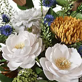 Decorative Floral Arrangement In Vase With White Roses Hydrangeas Blue Accent Flowers And Green Leaves