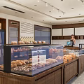 Cozy Dessert Shop Interior Featuring Wooden Counter Fresh Pastries And Bread On Shelves
