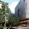 Modern Office Building Exterior With Metal Glass Facade And Surrounding Trees Greenery Pedestrians At Entrance