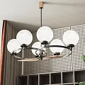 Modern Circular Chandelier With White Spherical Lampshades Black Metal Frame Perforated Wall And Green Plant