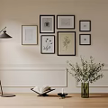 Elegant Photo Wall with Multiple Framed Artworks Floor Lamp Vase Greenery and Open Book