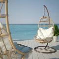 Wicker Hanging Chairs with White Cushions on Wooden Deck by Seaside View