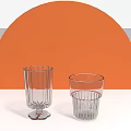 Transparent Glass Cups With Ribbed Design Against Orange Semicircle Background