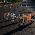 White Folding Electric Motorcycle Parked In Evening Stone Square With Buildings And Pedestrians