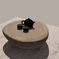Round Stone Coffee Table With Black Teapot And Two Small Teacups On Woven Rug