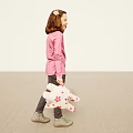 Cheerful Girl In Pink Long Sleeve Top Holding Polka Dot Cloth Standing On Beige Floor