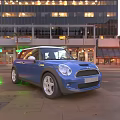 Blue Mini Cooper Car on Urban Street with Tall Buildings and Evening City Lights