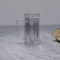 Transparent Glass Mug With Handle On Marble Countertop And Gold Accessory