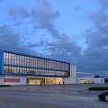 Modern Blue And White Office Building With Large Glass Windows And Parking Area