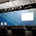 Modern Conference Room Interior With Blue Backdrop White Projection Screen Ceiling Lights And Black Seats