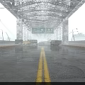 Dilapidated Steel Truss Bridge With Abandoned Vehicles Overhead Signage On Wet Puddled Road