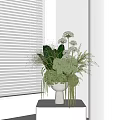 White Vase With Green Plants Round Flowers And Hanging Foliage By Window With Blinds