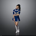 Young Woman In Blue And White Cheerleader Uniform Posing Against Gray Background