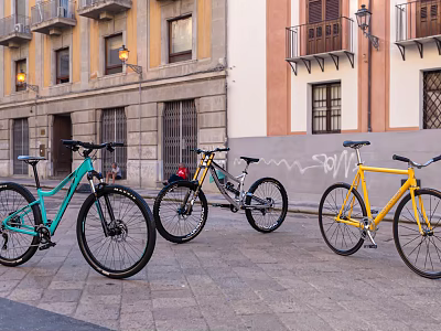 Three Colorful Bicycles Parked On Stone Paved Street With Graffiti Wall And Buildings 3d model