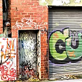 Red Brick Wall With Vibrant Graffiti Art And Colorful Designs On Roller Shutter Door