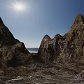 Rocky Terrain with Majestic Peaks Sunlit Under Clear Blue Sky and Distant Water View