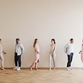Group of People Walking and Standing Against Light Wall on Wooden Floor
