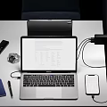Modern Laptop Work Setup With Connected Smartphone Charger Passport Watch And Pen