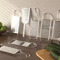 Stainless Steel Kitchen Graters on Wooden Table with Green Apples Zucchini and Cutting Board