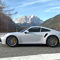 White Porsche Sports Car Parked Outdoor With Building And Mountain View
