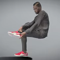 Man wearing gray long sleeve and gray pants lifting one leg to adjust red sneakers