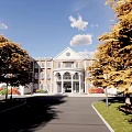 Elegant Classical Building with Red Bricks White Walls Porch Columns Autumn Trees Lawn and Bench