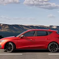 Red Sporty Compact Car Driving On Scenic Mountain Road With Clear Sky
