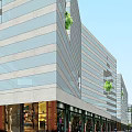 Vibrant Commercial Street With Modern Buildings Pedestrians Shops And Green Trees