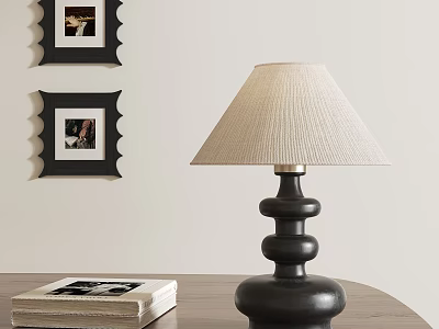 Black Base Table Lamp With Beige Linen Shade Near Stacked Books And Wall Frames 3d model
