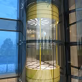 Modern Transparent Elevator with Glass Shaft and Gold Accents on Building Exterior