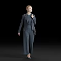 A woman in dark suit with blonde hair carrying small bag standing against black background