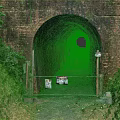 Road Infrastructure Featuring Brick Tunnel Entrance With Metal Gate Warning Signs And Green Vegetation