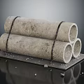 Concrete Pipes Bound With Black Straps Stacked On Black Platform With Gravel Scattered Around