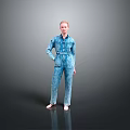 A Woman Standing Barefoot With Hands On Hips In Blue Denim Jumpsuit Against Gray Background